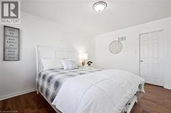 Bright room featuring wood-finish flooring, white baseboards, and a paneled white door - 