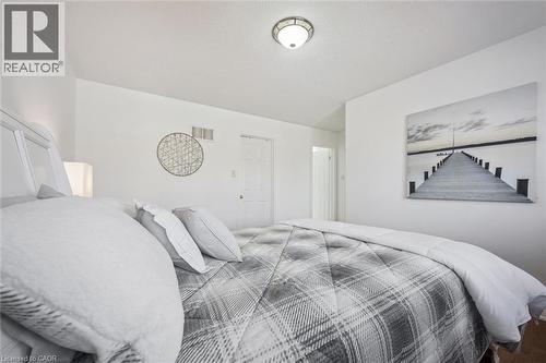 Spacious room featuring white walls, a textured ceiling, a flush-mount ceiling light fixture, and white interior doors - 5147 Ravine Crescent, Burlington, ON - Indoor Photo Showing Bedroom