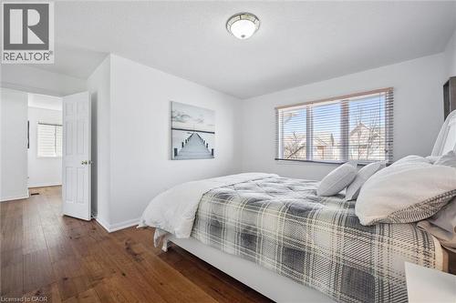 Spacious room featuring wood-finish flooring, a large window with blinds, and white trim - 5147 Ravine Crescent, Burlington, ON - Indoor Photo Showing Bedroom
