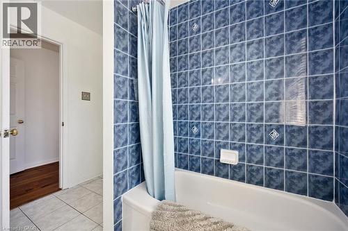 Bathtub with blue tiled surround featuring decorative square accents - 5147 Ravine Crescent, Burlington, ON - Indoor Photo Showing Bathroom