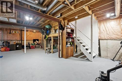 Unfinished basement offering expansive open space, exposed wood joists, structural steel beam, painted concrete flooring, and a white-painted staircase - 5147 Ravine Crescent, Burlington, ON - Indoor Photo Showing Basement