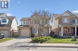 Two-story residence featuring a brick and siding exterior, an attached garage, and a paved driveway - 