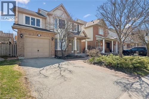 Two-story residence featuring a brick and siding exterior, an attached single-car garage, and a covered front porch with white railings - 5147 Ravine Crescent, Burlington, ON - Outdoor With Facade