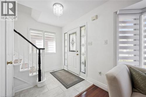 Foyer featuring a decorative glass paneled entry door, light-toned tile flooring, and a crystal chandelier - 5147 Ravine Crescent, Burlington, ON - Indoor Photo Showing Other Room