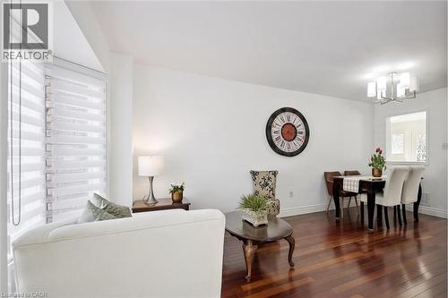 Spacious living area featuring polished wood-finish flooring, a bay window with contemporary blinds, and a built-in pass-through window to an adjacent room - 5147 Ravine Crescent, Burlington, ON - Indoor