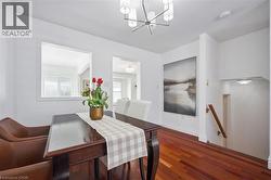 Dining area featuring rich wood-finish flooring, a contemporary chandelier, and an interior pass-through window - 