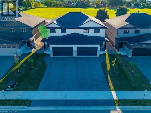 Modern semi-detached residence featuring a two-car garage, dark asphalt driveway, and light gray brick facade - 111 Amber Street, Waterford, ON - Outdoor