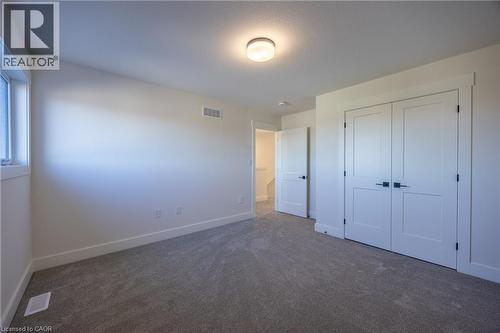 Carpeted room featuring a double-door closet with black hardware, a single window, and a flush-mount ceiling light - 111 Amber Street, Waterford, ON - Indoor Photo Showing Other Room
