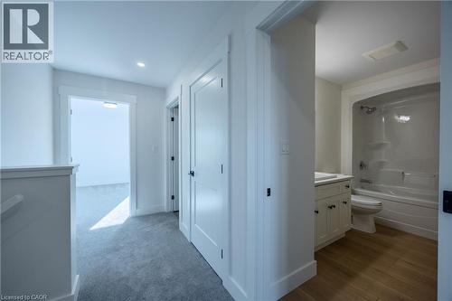 Hallway with light gray carpeting, white trim, and white doors - 111 Amber Street, Waterford, ON - Indoor Photo Showing Bathroom