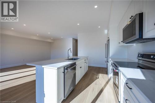 Open-concept kitchen featuring white shaker cabinetry, stainless steel appliances, light-toned wood-finish flooring, recessed lighting, and a kitchen island with an undermount sink - 111 Amber Street, Waterford, ON - Indoor Photo Showing Kitchen With Upgraded Kitchen