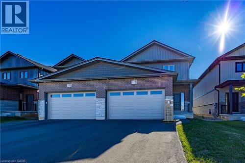 Contemporary residence featuring a brick and siding exterior with stone accents, a two-car garage with transom windows, and an asphalt driveway - 115 Amber Street, Waterford, ON - Outdoor With Facade