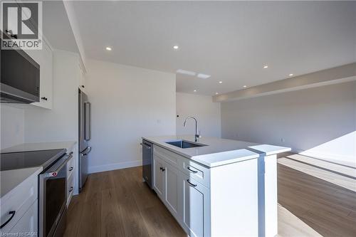 Modern kitchen featuring white shaker cabinetry, stainless steel appliances, a center island with sink and integrated dishwasher, and wood-finish flooring - 115 Amber Street, Waterford, ON - Indoor Photo Showing Kitchen With Upgraded Kitchen