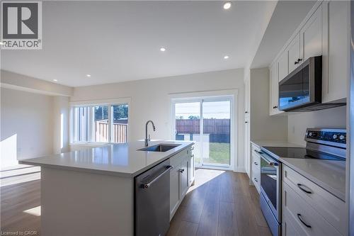 Modern kitchen featuring white shaker cabinetry, stainless steel appliances, a large center island with an undermount sink, and light wood-finish flooring - 115 Amber Street, Waterford, ON - Indoor Photo Showing Kitchen With Upgraded Kitchen