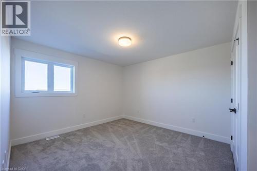 Bright interior room featuring a window with white trim, light gray carpet, white walls, and a flush mount ceiling light - 115 Amber Street, Waterford, ON - Indoor Photo Showing Other Room