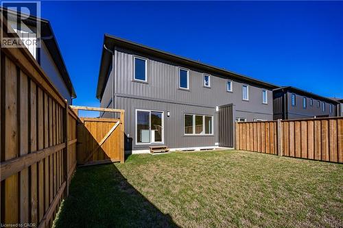 Fenced backyard featuring a manicured lawn, wood fencing, and a rear exterior with multiple windows and sliding glass door access - 115 Amber Street, Waterford, ON - Outdoor With Exterior
