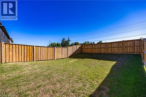 Expansive backyard featuring a manicured lawn, perimeter wood fencing, and clear sky overhead - 115 Amber Street, Waterford, ON - Outdoor