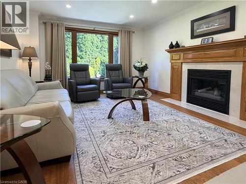 The inviting family room offers a gas fireplace, hardwood flooring and a large picture window overlooking the beautifully landscaped backyard - 7 Mann Avenue, Simcoe, ON - Indoor Photo Showing Living Room With Fireplace