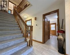 Carpeted staircase to the upper level featuring wooden newel posts and spindles. Door to main floor lauundy at right. - 