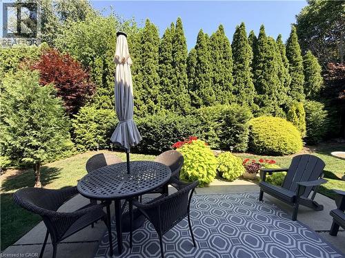 Step outside to your own private retreat, where towering mature trees and a lush hedge create exceptional privacy. The concrete patio, perennial gardens, sprinkler system, and mature beautifully lands - 7 Mann Avenue, Simcoe, ON - Outdoor With Deck Patio Veranda