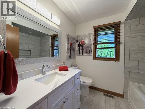 Bathroom featuring a white vanity with an integrated rectangular sink, chrome faucet, and a quartz-finish countertop, tiles shower. - 7 Mann Avenue, Simcoe, ON - Indoor Photo Showing Bathroom