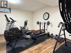 Dedicated fitness area featuring wood-finish flooring, a flush-mount ceiling light, and a horizontal window with wood trim - 