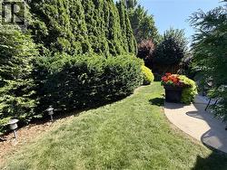 Landscaped garden path featuring a manicured lawn, established hedges, and a curved concrete patio - 