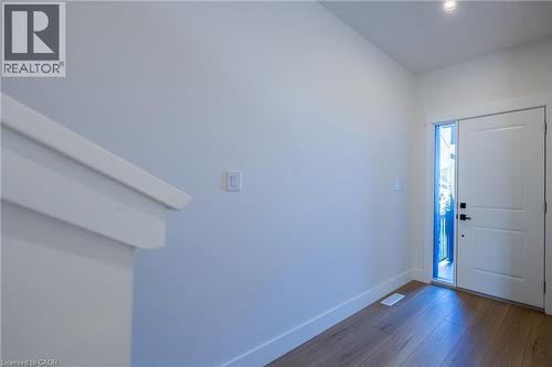 Entryway featuring wood-finish flooring, white baseboards, a white paneled door with a black handle, and an adjacent full-length vertical window - 107 Amber Street, Waterford, ON - Indoor Photo Showing Other Room