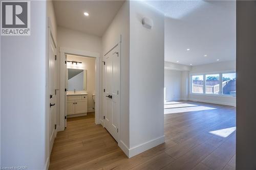 Entryway featuring wood-finish flooring, white trim, recessed lighting, and a powder room with a vanity, rectangular sink, and wall-mounted light fixture - 107 Amber Street, Waterford, ON - Indoor Photo Showing Other Room