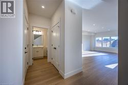 Entryway featuring wood-finish flooring, white trim, recessed lighting, and a powder room with a vanity, rectangular sink, and wall-mounted light fixture - 