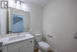 Bathroom featuring a white vanity with an undermount sink, a chrome faucet, and a large wall-mounted mirror - 