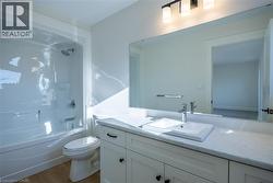 Bathroom featuring a white vanity with recessed panel cabinetry, an integrated sink, and a light-toned countertop - 