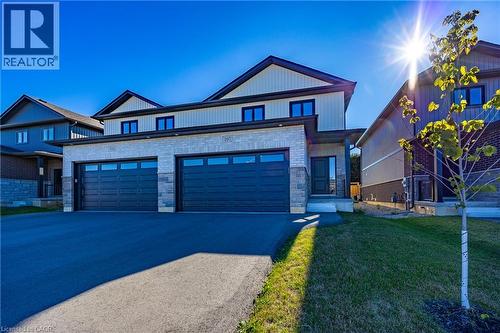 Modern two-story residence featuring a combination of stone and siding exterior, a two-car garage with panel doors and window inserts, a paved driveway, and a covered entry - 107 Amber Street, Waterford, ON - Outdoor With Facade