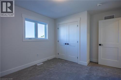 Bright room featuring a double window with white trim, gray carpet flooring, and a double-door closet with black hardware - 107 Amber Street, Waterford, ON - Indoor Photo Showing Other Room