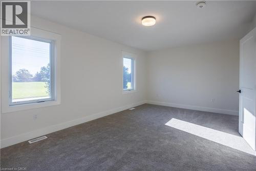 Neutral wall tones with two windows, recessed ceiling light, and gray carpeting - 107 Amber Street, Waterford, ON - Indoor Photo Showing Other Room