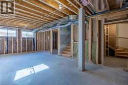 Unfinished basement featuring exposed wood joists, concrete flooring, and framed walls with insulation - 