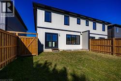 Expansive grassy yard with a wooden privacy fence, featuring a contemporary white siding exterior with contrasting black trim - 