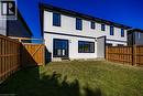 Expansive grassy yard with a wooden privacy fence, featuring a contemporary white siding exterior with contrasting black trim - 107 Amber Street, Waterford, ON  - Outdoor 