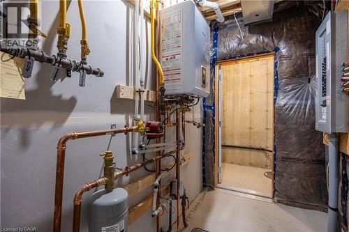 Utility room featuring an on-demand water heater, copper piping, PEX plumbing, and a circuit breaker panel - 107 Amber Street, Waterford, ON - Indoor Photo Showing Basement