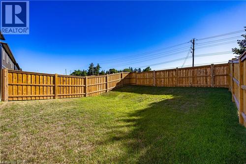 Expansive backyard featuring a new perimeter wood fence, a large grass area, and a gradual slope - 107 Amber Street, Waterford, ON - Outdoor