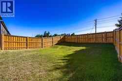 Expansive backyard featuring a new perimeter wood fence, a large grass area, and a gradual slope - 