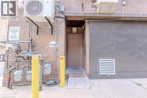 Brick exterior featuring a utility door with an access ramp, adjacent to a large gray panel - 96 Gerrard St E, Toronto, ON 