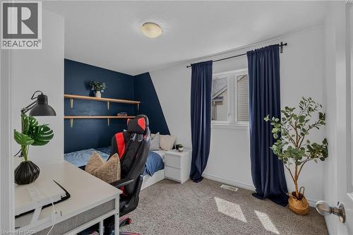 Carpeted room featuring a window with dark drapery, a partial accent wall, and built-in wall shelving - 174 Woodway Trail, Simcoe, ON - Indoor