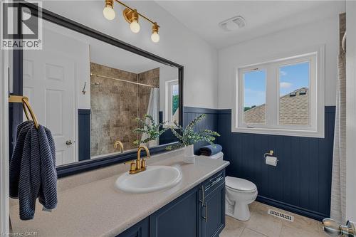 Contemporary bathroom featuring a vanity with a light-colored countertop, an undermount sink, and brass fixtures - 174 Woodway Trail, Simcoe, ON - Indoor Photo Showing Bathroom