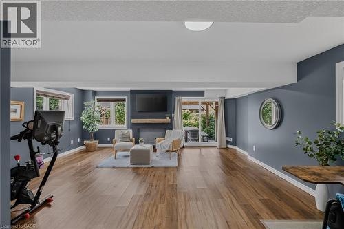 Spacious living area featuring wood-finish flooring, recessed lighting, and a fireplace with a substantial wood mantel - 174 Woodway Trail, Simcoe, ON - Indoor Photo Showing Living Room With Fireplace