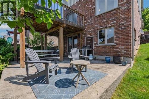 Lower-level patio featuring stamped concrete, a grassed area, and a covered wooden deck structure - 174 Woodway Trail, Simcoe, ON - Outdoor With Deck Patio Veranda