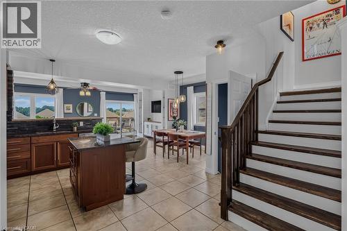 Open-concept kitchen and dining area featuring tile flooring, dark wood cabinetry, and a central island with a granite-style countertop - 174 Woodway Trail, Simcoe, ON - Indoor Photo Showing Other Room
