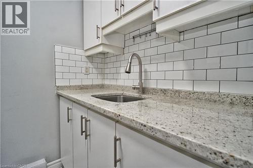 Kitchen area featuring white cabinetry with brushed nickel hardware, a stainless steel sink with a high-arc faucet, and light-toned speckled countertops - 119 Cedar Street S Unit# 14, Kitchener, ON - Indoor Photo Showing Kitchen