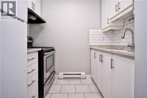 Kitchen featuring white cabinetry with brushed nickel hardware, speckled countertops, subway tile backsplash, and stainless steel appliances - 119 Cedar Street S Unit# 14, Kitchener, ON - Indoor Photo Showing Kitchen