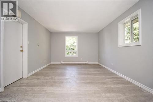 Spacious room featuring light grey walls, wood-finish flooring, white trim, and two windows providing natural light - 119 Cedar Street S Unit# 14, Kitchener, ON - Indoor Photo Showing Other Room