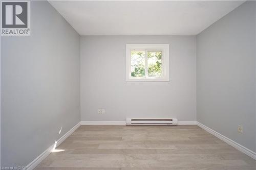Neutral-toned room featuring a window with white trim, light wood-finish flooring, and white baseboards - 119 Cedar Street S Unit# 14, Kitchener, ON - Indoor Photo Showing Other Room